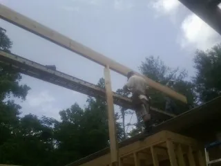 Carpenter setting a ridge beam over a new addition frame — Ice Dam Removal by Roofing Brothers in Covington