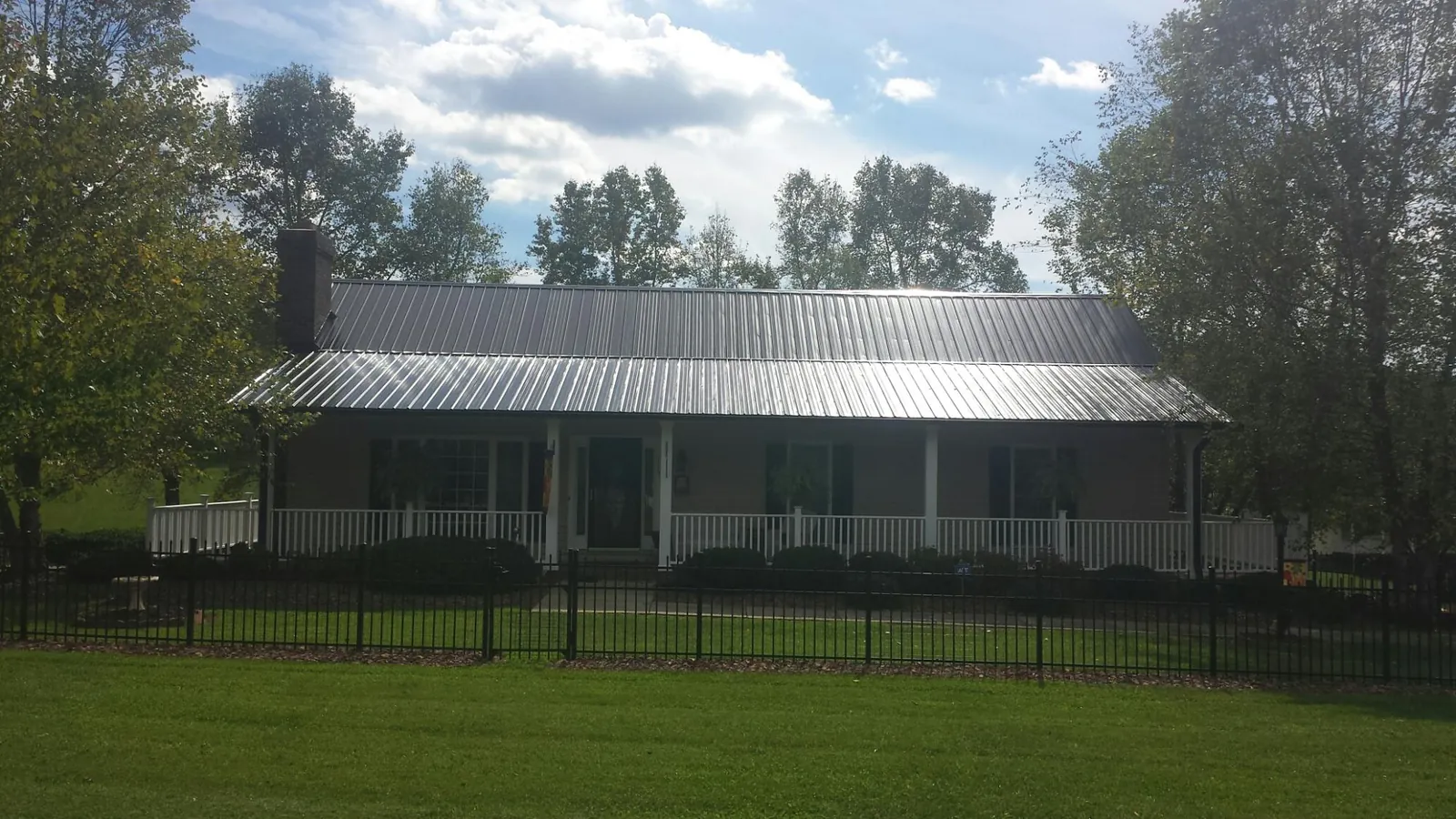 Gray metal roof on a brick ranch with a full width front porch — Gutter Guard Installation work by our crew in Covington